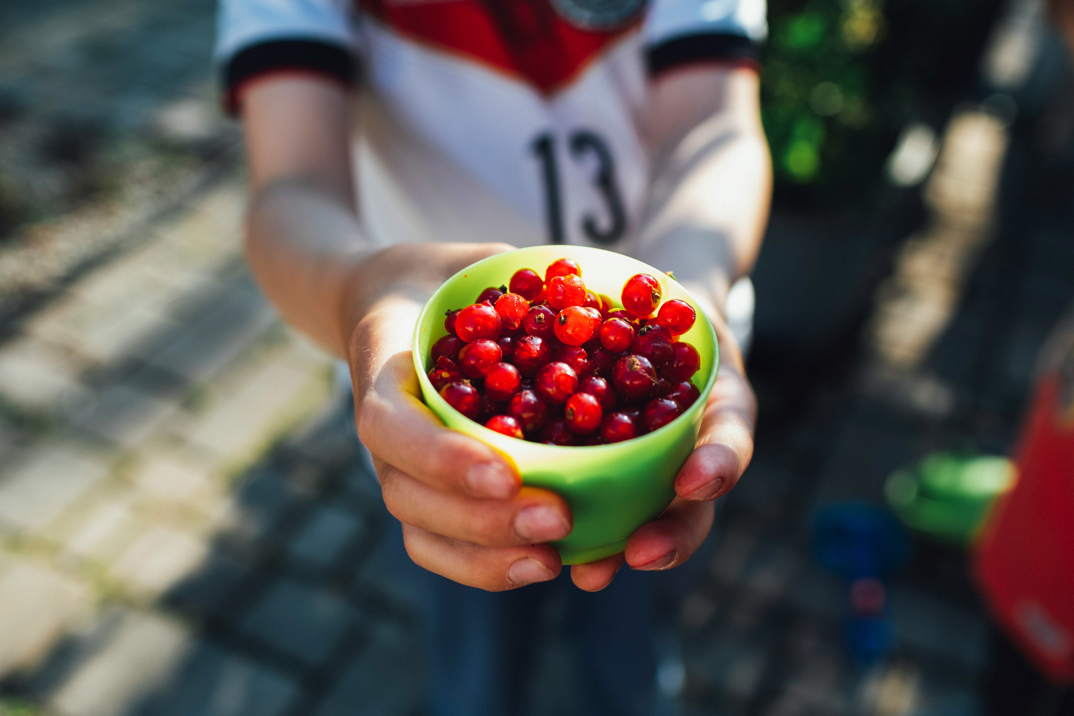 person holding green ceramic bowl with red and white fruits